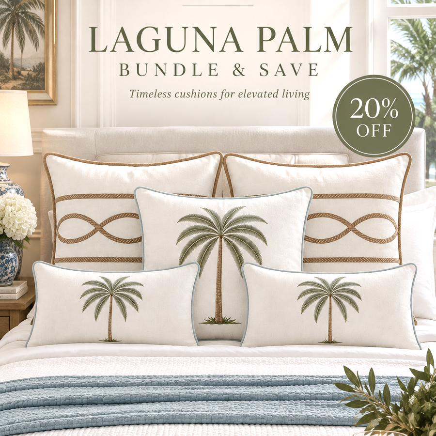 A styled bedroom scene featuring a bed dressed in white and light blue bedding with multiple decorative pillows, including two white pillows printed with green palm tree motifs and one larger back pillow with a gold infinity symbol. Text overlays read 'PALOMA LIVING SYDNEY', 'LAGUNA PALM BUNDLE & SAVE', and '20% OFF'.